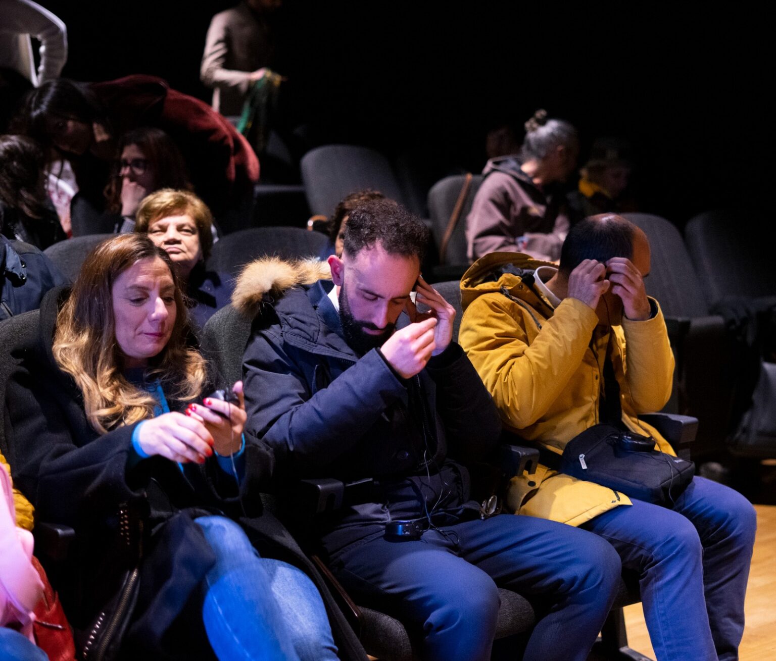 Tre spettatori seduti in prima fila che attendono l'inizio del film